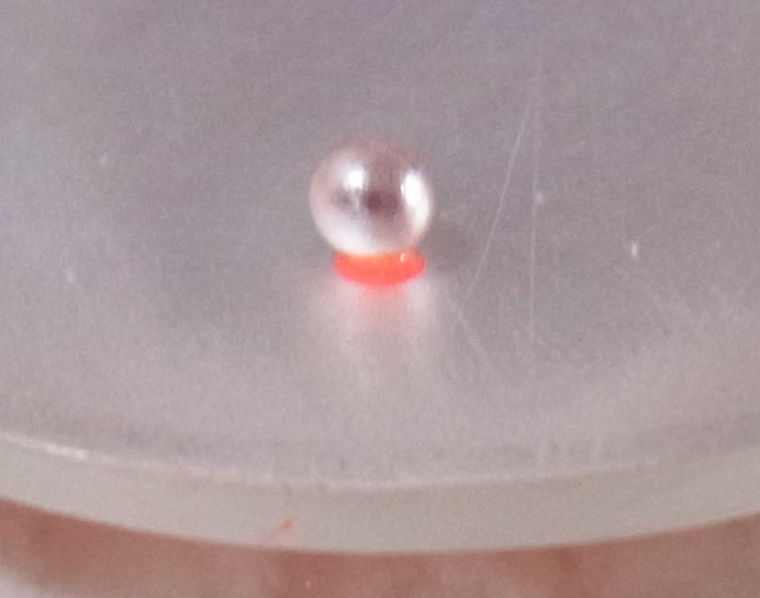 The paste beneath the silver granule glows red and melts.